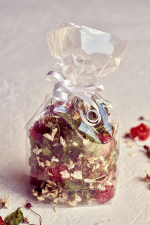 Homemade tea mix made from cherry blossoms, young leaves and dried fruit in a cellophane bag on white backgroundの写真素材