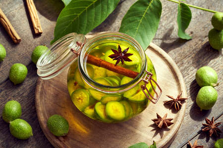 Macerating unripe walnuts and spices in alcohol in a jar, to prepare homemade nut liqueur or tinctureの写真素材