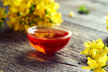 A bowl of red oil made from St. John's wort flowers - alternative herbal remedyの写真素材