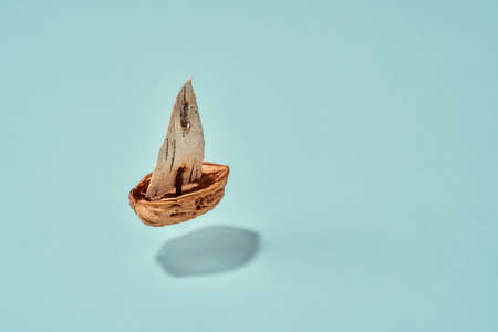 Summer concept with a boat made from a nut shell and birch bark floating over blue turquoise...