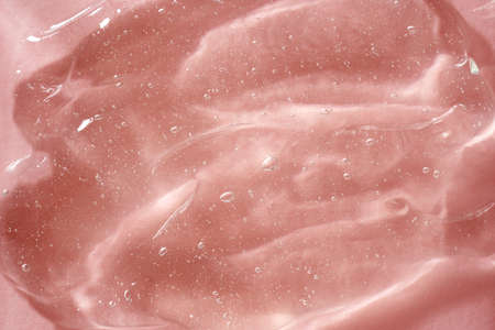 Transparent aloe vera gel on pink background, close up