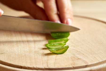 Slices of aloe vera leaves, with a knife and hand in the background