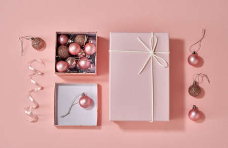 Boxes with Christmas presents and ornaments on pastel pink background, top view