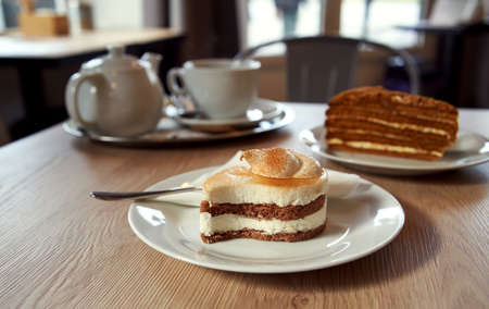 Cake with mascarpone and cinnamon a table in a cafe, with a cup of tea and teapot in the background