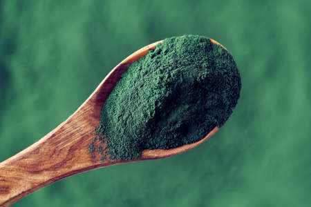 Green spirulina powder on a spoon, top viewの写真素材