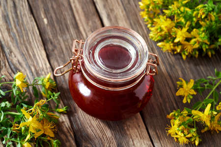 A bottle of red oil made from St. John's wort flowers, with fresh Hypericum perforatum plantの写真素材