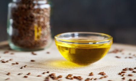 Flax seed oil in a bowl with linseeds in the backgroundの写真素材