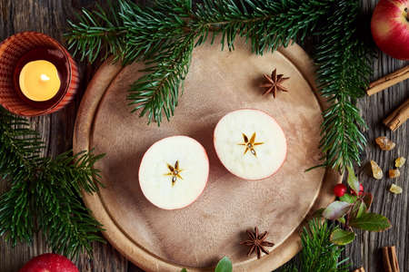 Christmas decoration with fir thee branches, cinnamon, frankincense and a halved apple with a star in the middleの写真素材