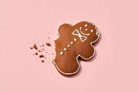 Smiing gingerbread Christmas man without a leg on pastel pink background