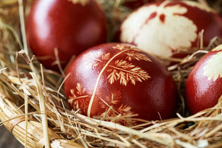 Detail of Easter eggs dyed with onion peels with a pattern of fresh herbs in a wicker basketの写真素材