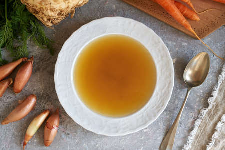 A plate of beef bone broth with fresh vegetables, top viewの写真素材