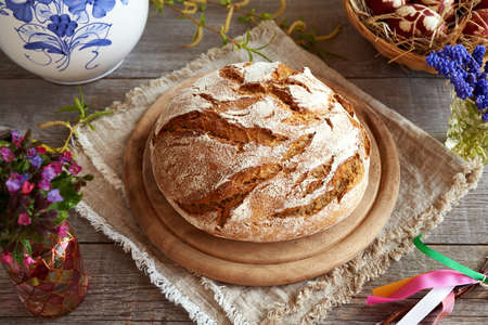 Sourdough bread with Easter eggs, spring flowers and typical Czech whip called pomlazka