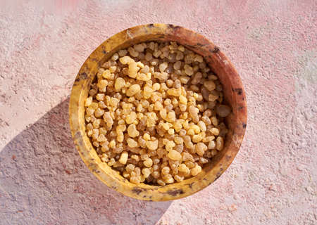 Frankincense resin crystals in a bowl on pink background in sunlight, top viewの写真素材