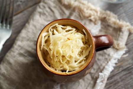 Homemade fermented cabbage or sauerkraut in a pot on a table, top viewの写真素材