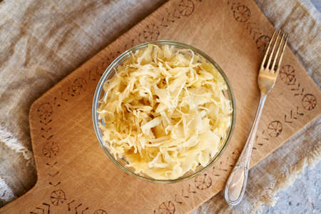 Homemade fermented cabbage or sauerkraut in a glass bowl with a fork, top view