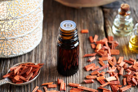 A dropper bottle of essential oil with red sandalwood chips
