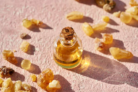 A bottle of aromatherapy essential oil with frankincense resin on a pastel pink backgroundの写真素材