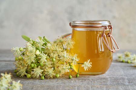 Fresh linden flowers with a jar of honey on a tableの写真素材