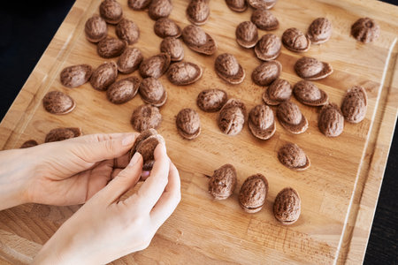 Preparation of cocoa Christmas cookies in the form of nuts - filling the halves with creamの写真素材