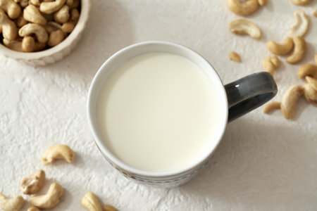 A cup of vegan cashew nut milk on a white table, top viewの写真素材