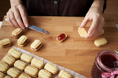 Filling Christmas cookies with strawberry jamの写真素材