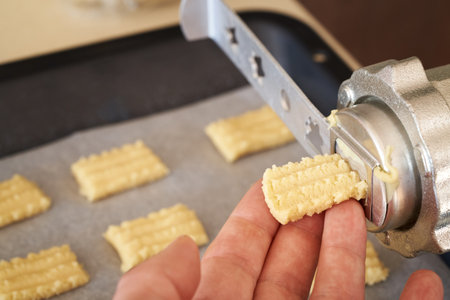 Pressing sweet dough through a machine to prepare homemade Christmas pastryの写真素材