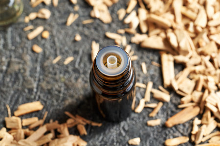 Essential oil bottle with white sandalwood chips on a tableの写真素材