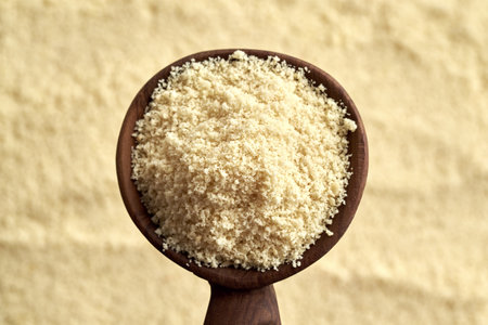 Alond flour on a wooden spoon, top view