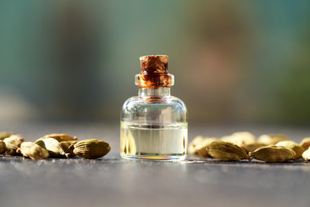 A glass bottle of aromatherapy essential oil with cardamom seeds in sunlightの写真素材
