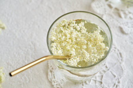 Fresh elderberry flowers in a glass of lemonade with a golden metal straw. Zero waste concept.の写真素材