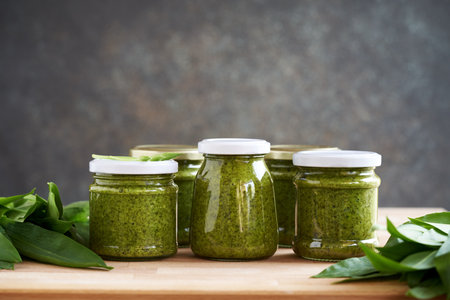 Jars of preserved green wild garlic or Allium ursinum pesto with fresh leaves, with copy spaceの写真素材