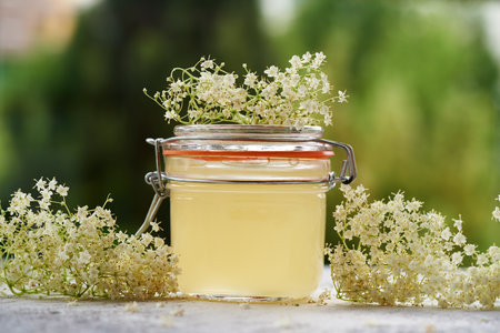 A jar of homemade elderberry flower syrup on a tableの写真素材