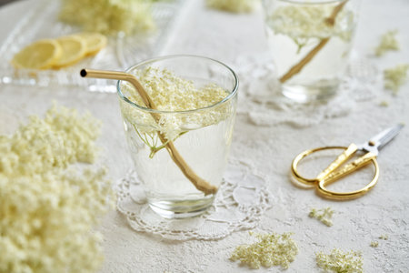 A glass of homemade lemonade with fresh elderberry flowers and a golden metal strawの写真素材