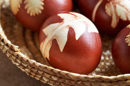 Easter eggs dyed with onion peels with a pattern of dandelion leaves in a basketの写真素材