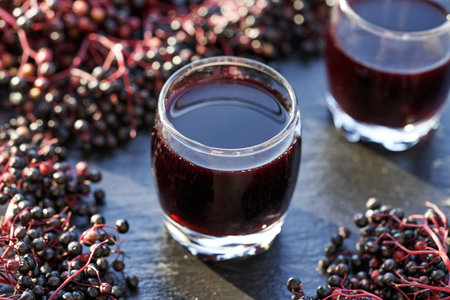 Black elderberry syrup in a glass cup with fresh berriesの写真素材