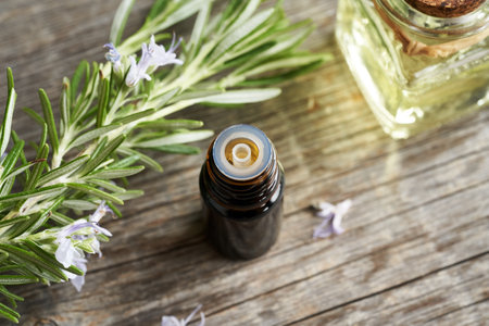 Closeup of a dark bottle of essential oil with fresh rosemary twigs and flowersの写真素材