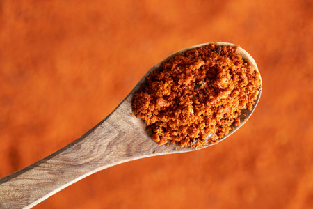 Sea buckthorn berry powder including seeds on a wooden spoon, top view