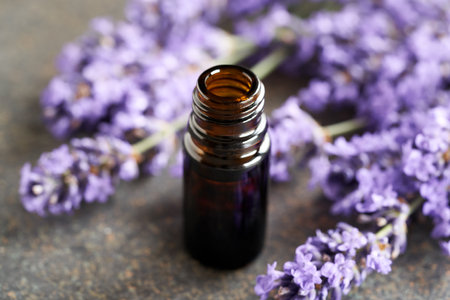 A brown bottle of aromatherapy essential oil with fresh blooming lavender on dark backgroundの写真素材