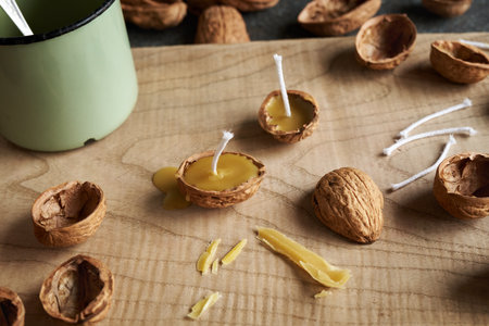 Handmade fabrication of Christmas candles from bees wax and nut shells on a table