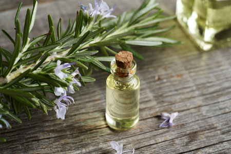 A bottle of aromatherapy essential oil with fresh blooming rosemary, close upの写真素材