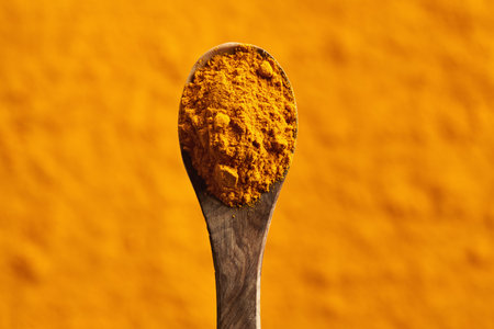Dry turmeric powder on a spoon, top view