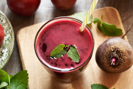 A glass of red beet juice with apples and melissa leavesの写真素材