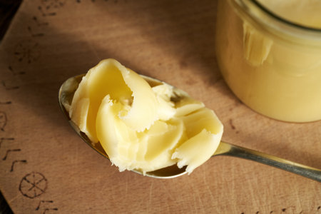 Ghee or clarified butter on a spoon near a glass jar, close upの写真素材