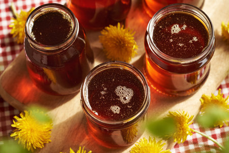 Several glass jars of dandelion honey - syrup made from fresh Taraxacum flowers in springの写真素材