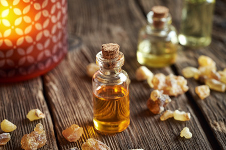 A transparent bottle of frankincense essential oil with boswellia resin and a candleの写真素材