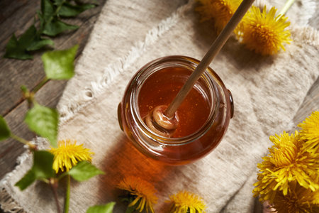 A jar of dandelion honey - syrup made from fresh Taraxacum flowers in spring, top viewの写真素材