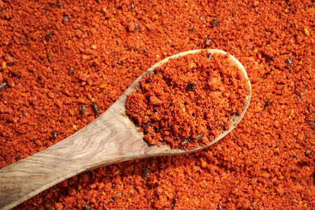 Dried sea buckthorn powder with seeds on a wooden spoon, closeup