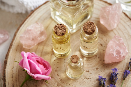 Several bottles of aromatherapy essential oil with rose de Mai and lavender flowers and rose quartz gem stonesの写真素材