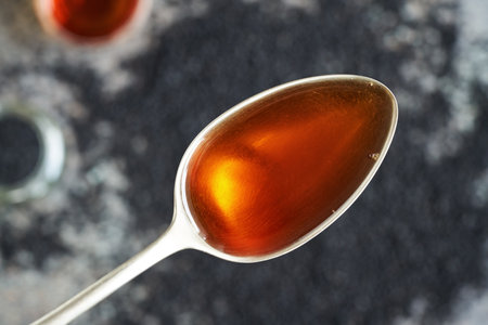 Black cumin or Nigella sativa seed oil on a metal spoon, top view. Healthy anti-inflammatory and antioxidant supplement.の写真素材
