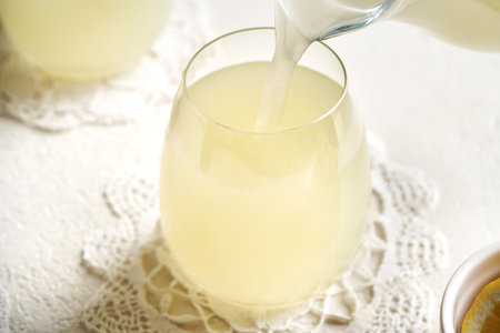 Pouring fresh whey into a glass cup on a white tableの写真素材